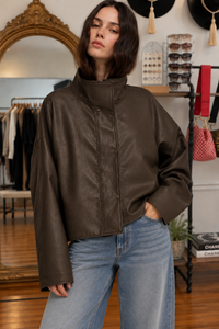 Woman wearing a chocolate brown oversized coated jacket with a high collar and blue denim jeans