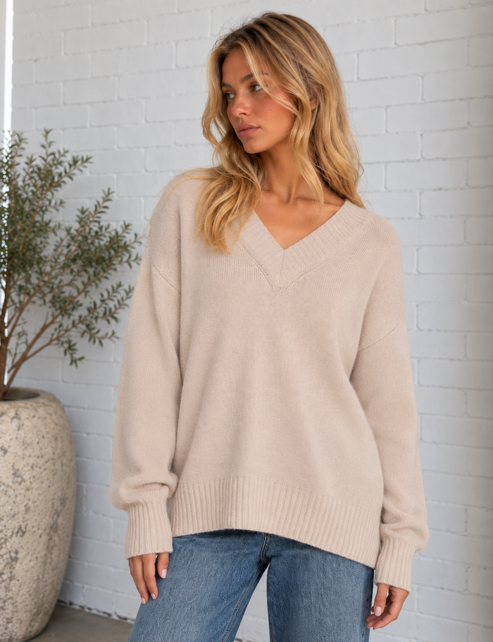Model wearing the Cloud Spun V-Neck Sweater in frosted pearl, featuring a relaxed fit, soft knit texture and wide ribbed V-neckline.