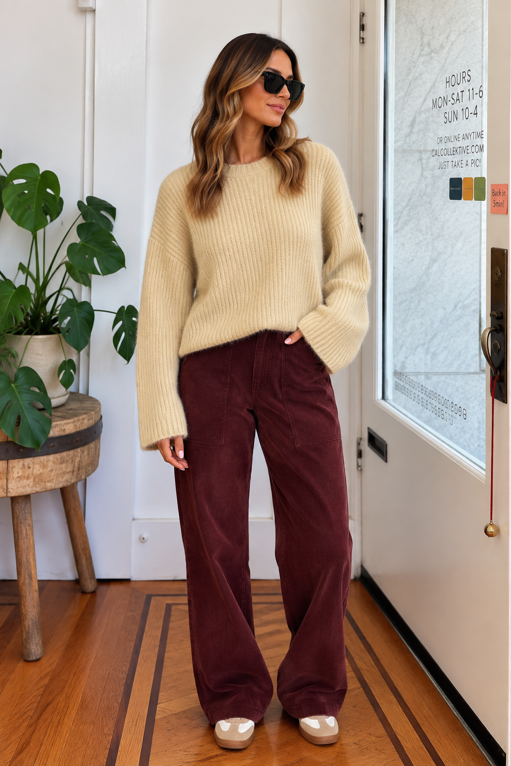 Woman wearing a cream relaxed fit knit sweater with burgundy corduroy pants