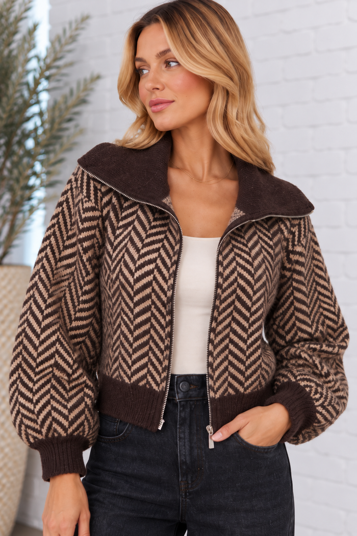 Front view of the Herringbone Zip Front Cardigan in chocolate brown and taupe, featuring a bold herringbone pattern, oversized collar, balloon sleeves, and zip-front closure.