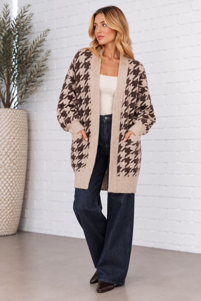 Blonde model wearing the taupe and dark brown houndstooth sweater cardigan, featuring an open front, oversized fit, ribbed trim, and front patch pockets.
