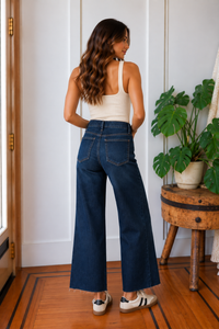 Back view of the Meg high rise wide leg jeans in dark indigo with cropped raw hems and back patch pockets