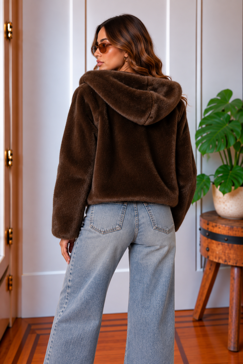 Back view of the Saskia chocolate brown faux fur hooded jacket styled with light wash wide leg jeans