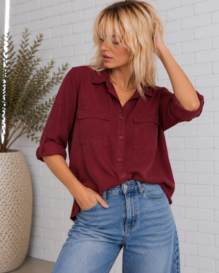 Blonde model wearing the Talma Shirt in Bordeaux, featuring a collared neckline, button-front closure, two chest flap pockets, and rolled sleeves.